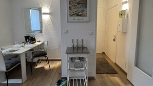 Un espacio habitable compacto con comedor, una kitchenette pequeña y una obra de arte enmarcada en la pared.