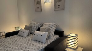 Un dormitorio ordenado con una colcha estampada, varios almohadones y lámparas de noche.