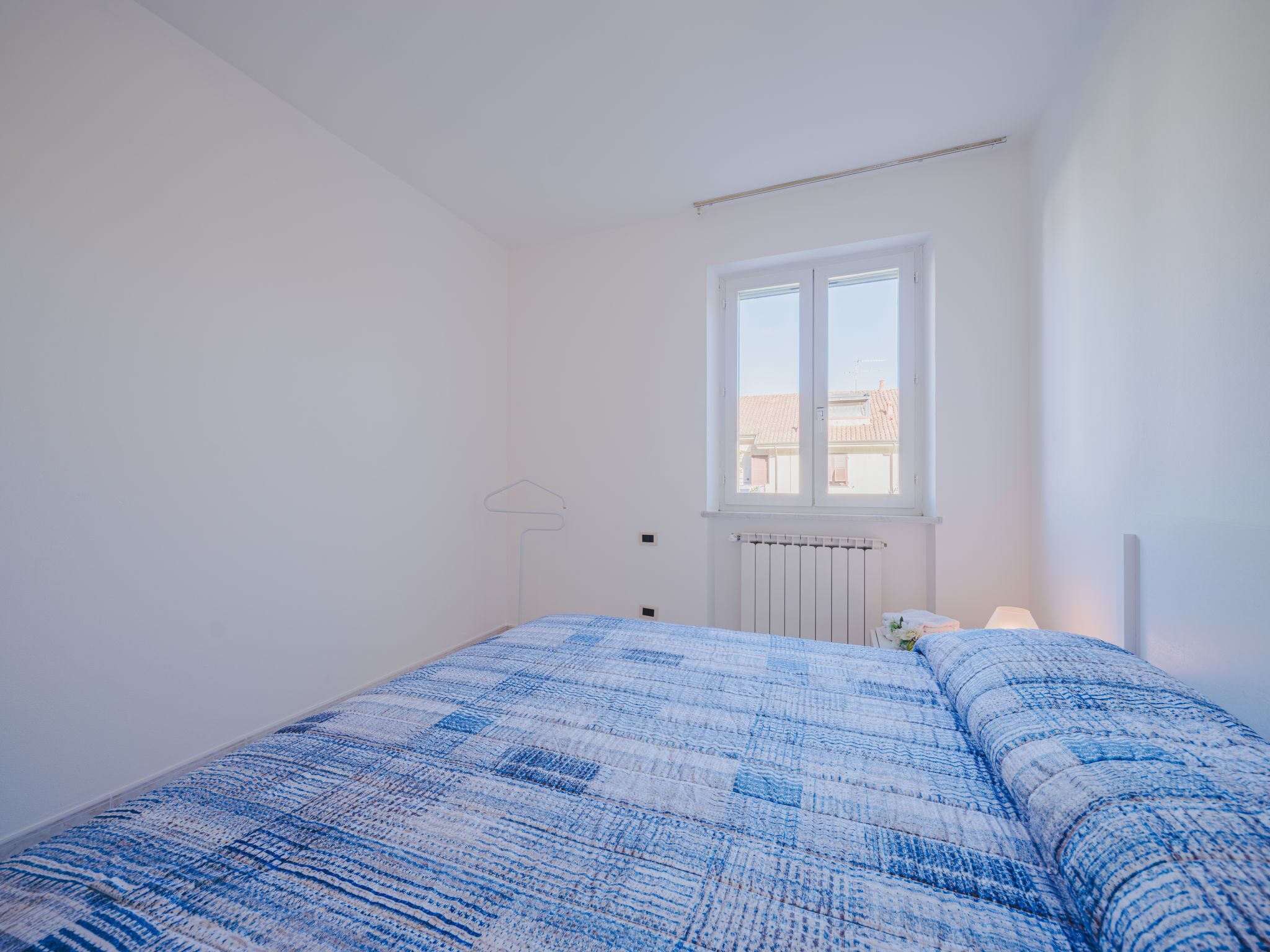 Une chambre à coucher avec un grand lit, une fenêtre et un radiateur.