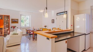 A modern kitchen with a central island, white cabinetry, and a dining area with a sofa and chairs. - Lucerna Due by Interhome (Ameglia)
