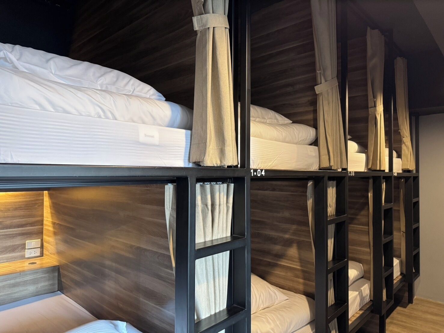 Habitación con literas de madera y cortinas en cada litera.
