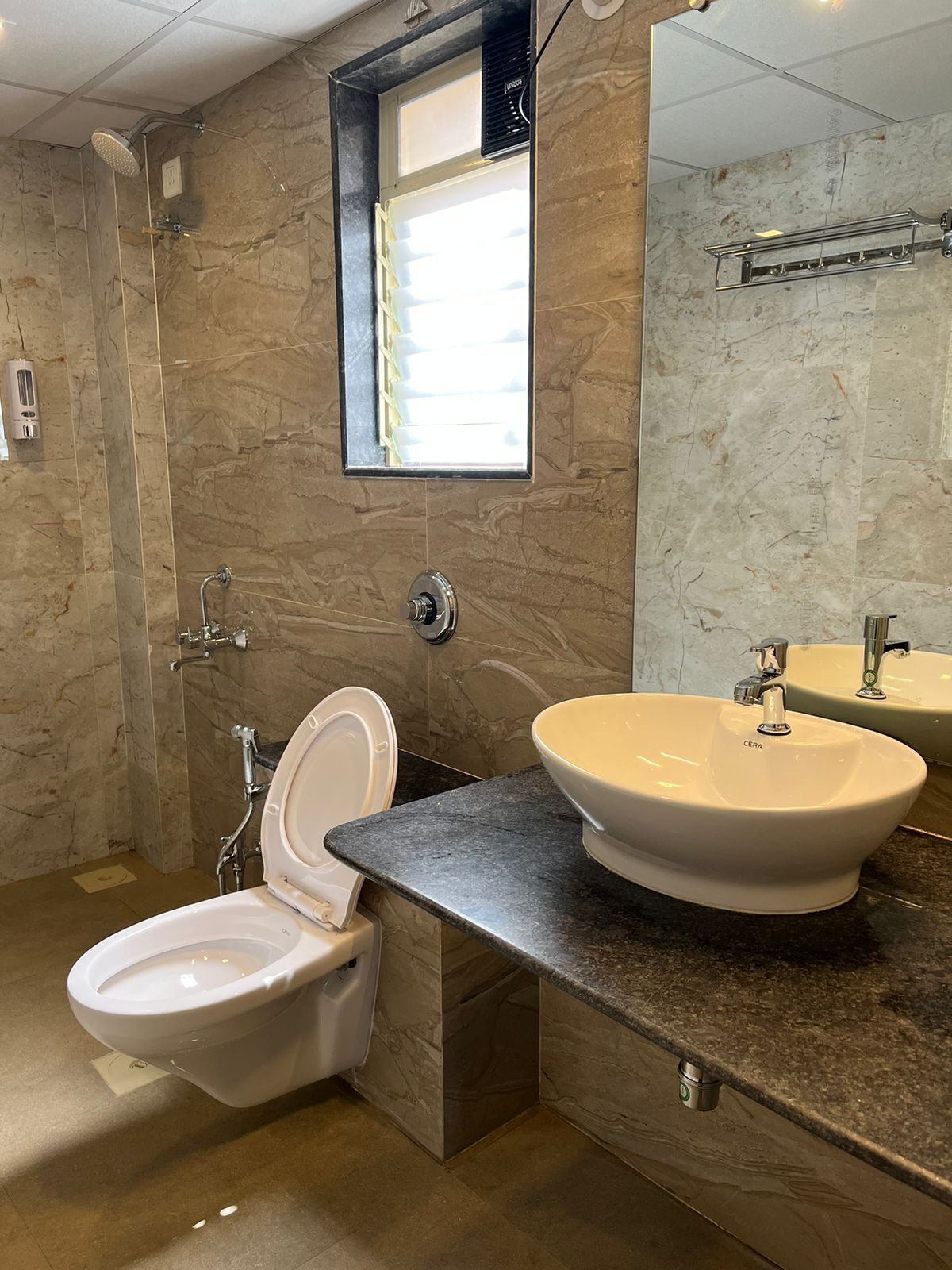 Et moderne badeværelse med toilet, håndvask og bruser.