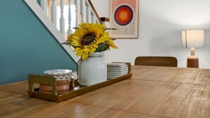 A dining table with a vase of sunflowers, a candle, and a tray with jars. - Coffee Lover's Paradise - Heart of Tremont (Cleveland)