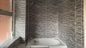 A modern bathroom with a freestanding bathtub, a shower with a handheld showerhead, and a vent on the wall. - Oxford-house-sleeps 7-parking-garden (Oxford)