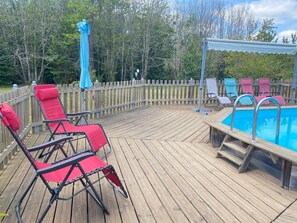 A wooden deck with a pool, red lounge chairs, and a blue umbrella. - Wooden house with private pool and WiFi in the heart of Périgord (Saint-Chamassy)