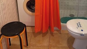 Un bany amb vàter, rentadora i un petit tamboret.