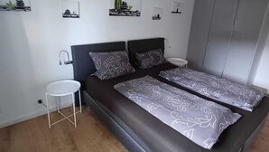 Moderni makuuhuone, jossa on suuri sänky, pieni yöpöytä ja riippuvalaisin.