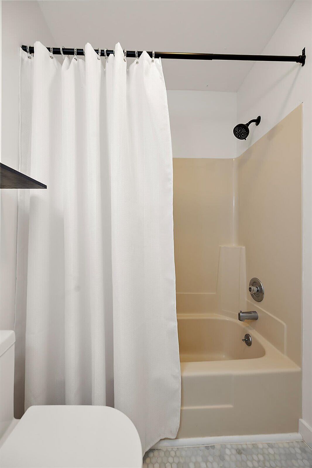 A bathroom with a bathtub, a showerhead, and a toilet.
