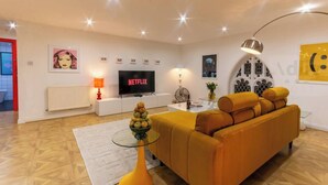 Een moderne woonkamer met een bank, een glazen salontafel, een televisie en een decoratieve lamp.