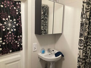 Un bagno con un lavandino bianco, uno specchio e tende a motivi decorativi.