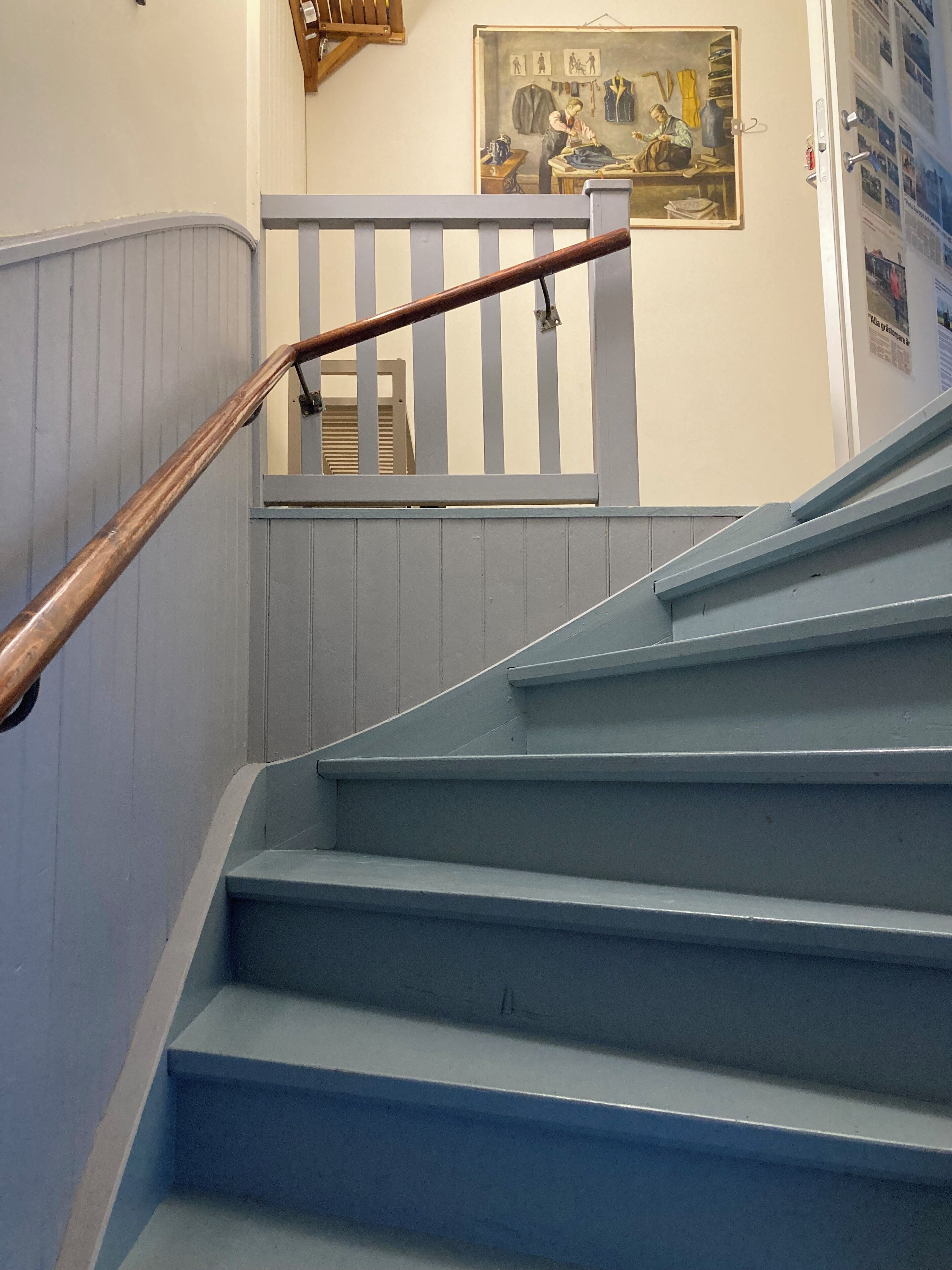 A staircase with blue steps and a wooden handrail.