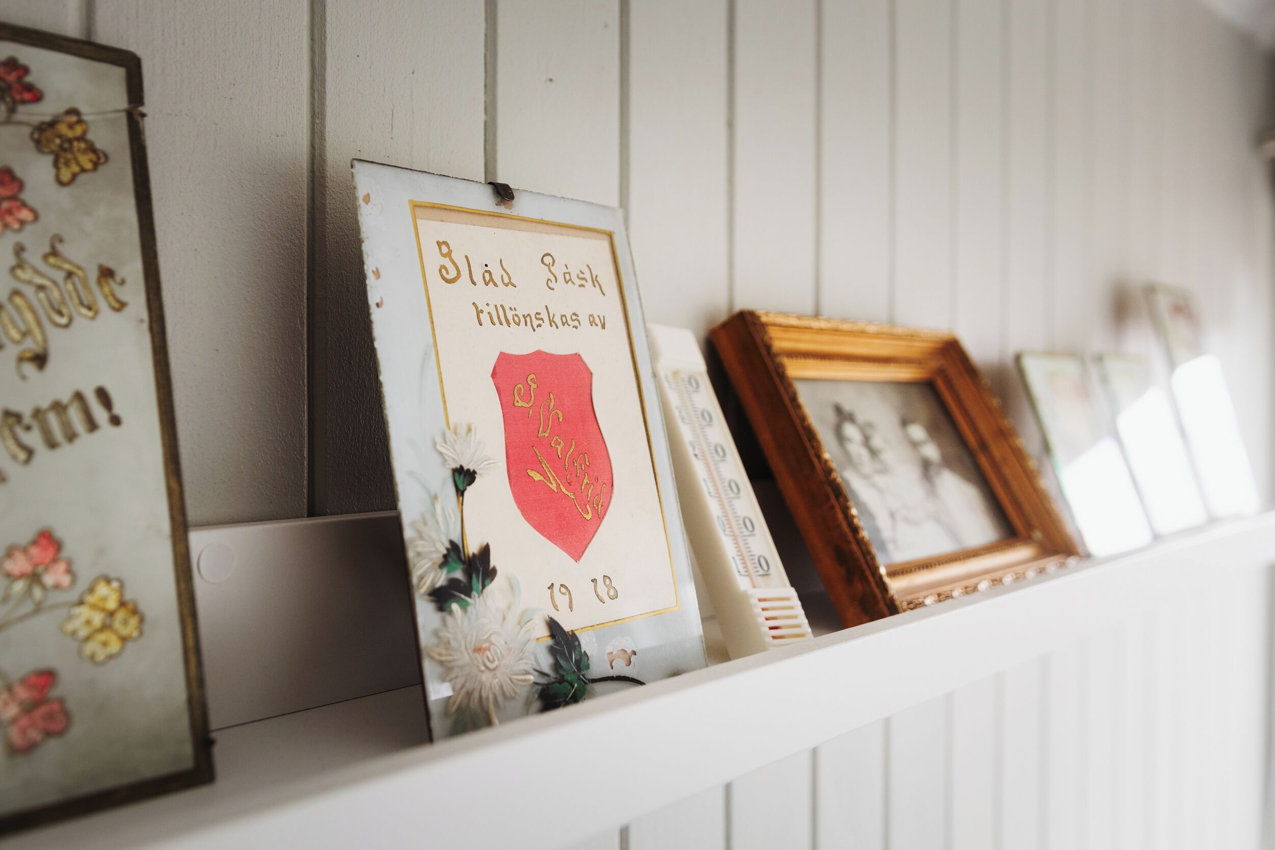 Une étagère avec des objets encadrés, notamment une enseigne avec du texte et un emblème en forme de cœur rouge.