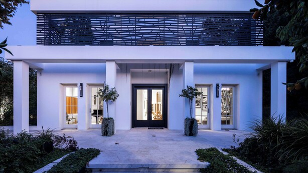 A modern two-story building with a black door, white walls, and a balcony with a black railing. - Carmelo  Tulip Villa (Kfar Shmaryahu)