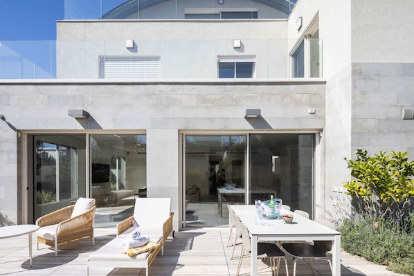 A modern house with a patio area featuring outdoor furniture and a dining table.