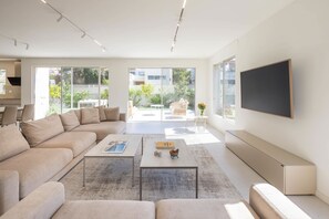 A modern living room with a large sofa, two coffee tables, and a flat-screen TV mounted on the wall. - Carmelo M Sea View Villa (Herzliya)