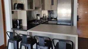 Una cocina moderna con una isla central, electrodomésticos de acero inoxidable y taburetes de bar.
