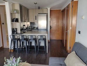 Une cuisine moderne avec un îlot central, des tabourets de bar, un canapé et une porte en bois.