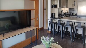 Una cocina moderna con una isla central, taburetes de bar y un televisor de pantalla plana.