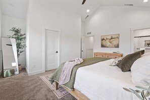 A bedroom with a bed, a dresser, a mirror, a door, and a painting on the wall.