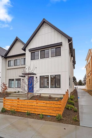 A modern two-story house with a flat roof, large windows, and a blue door.