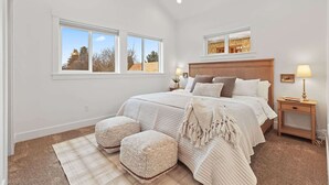 Una camera da letto con un letto grande, due comodini, una finestra con vista e un pavimento tappezzato.