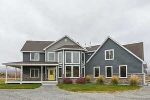A two-story house with a stone foundation, a wrap-around porch, and a large front door.