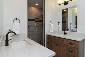 A modern bathroom with a marble sink, wooden cabinets, and a large mirror.