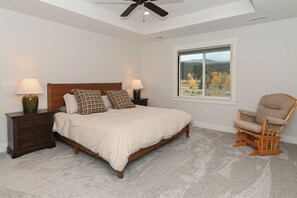A bedroom with a bed, nightstands, a chair, and a window with a view.