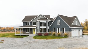 A two-story house with a covered porch, a stone foundation, and a garage. - Cabin getaway on 10 acres w/ wifi and fishing pond in Swan Valley (Swan Valley)