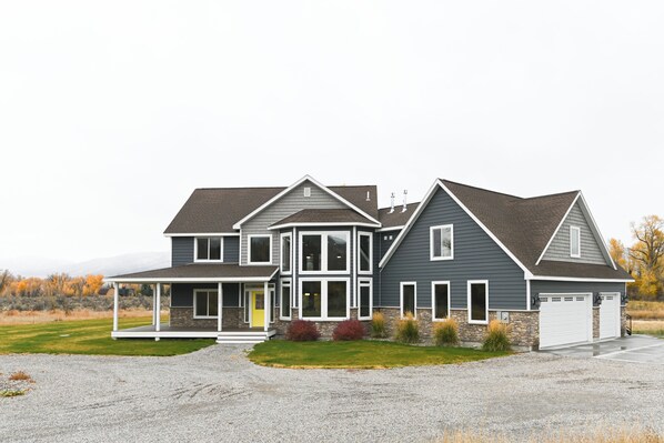 A two-story house with a covered porch, a stone foundation, and a garage.