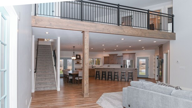 A spacious living area with a high ceiling, a staircase leading to an upper level, and a kitchen area visible in the background. - Cabin getaway on 10 acres w/ wifi and fishing pond in Swan Valley (Swan Valley)