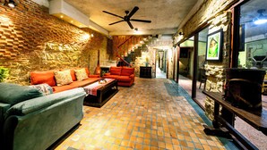 A cozy living area with a brick wall, a ceiling fan, and a tiled floor. - Outstanding  3BR villa at 50 m away from the white-sand of Hoi An beach. (phường Cẩm An)