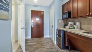 A modern kitchen with wooden cabinets, a microwave, and a coffee maker.