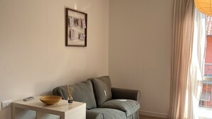 Een minimalistische woonkamer met een grijze bank, een witte bijzettafel en een lijst met een foto aan de muur.