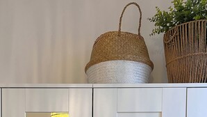 Een witte garderobe met spiegel, een bed met wit beddengoed en een hangmand met groen.