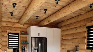 Una cocina moderna con una isla central, taburetes de bar, un refrigerador y vigas de madera en el techo.