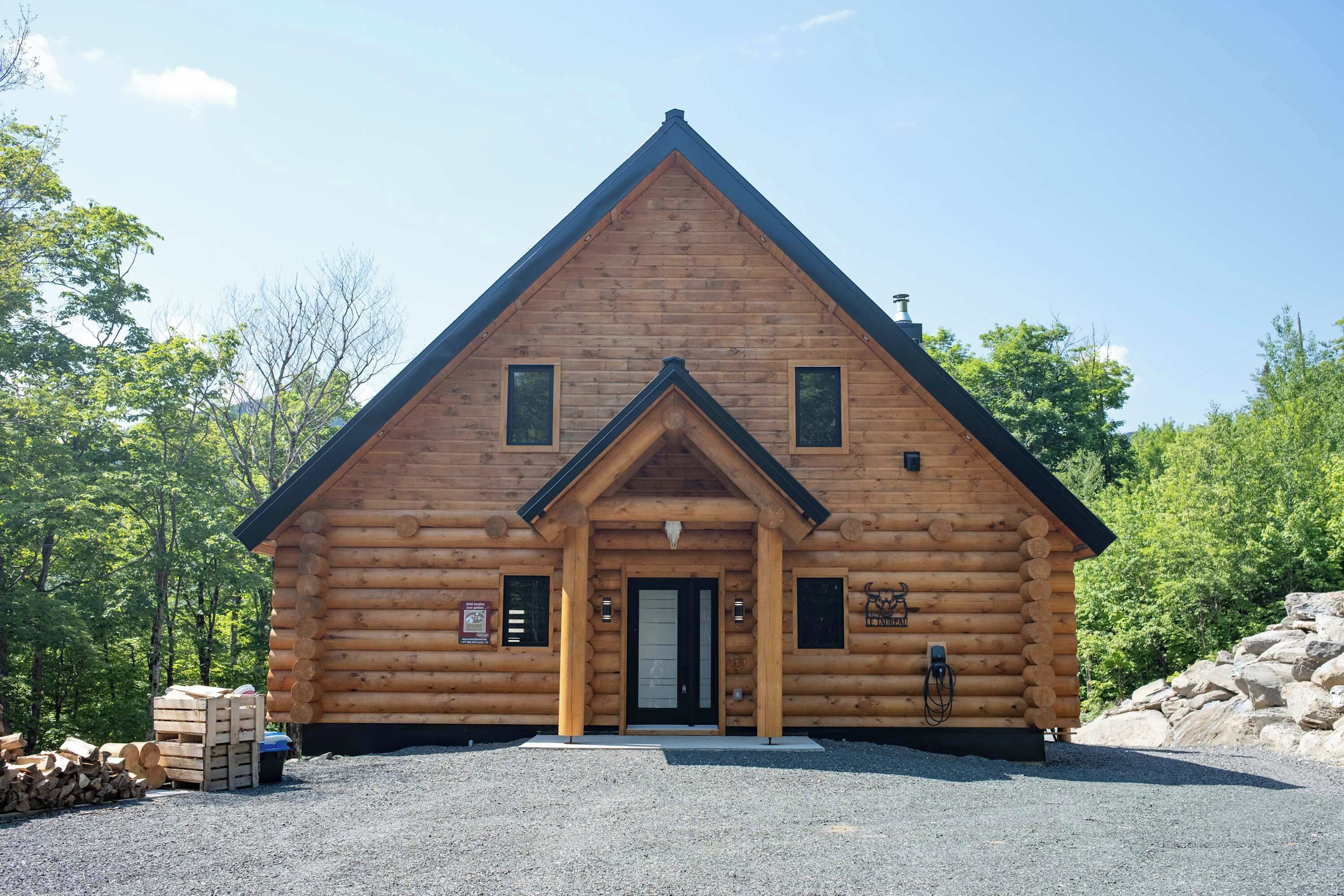 Una cabaña de madera con techo triangular, una puerta principal y dos ventanas.