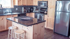 A kitchen with wooden cabinets, a stainless steel refrigerator, a microwave, and a sink.