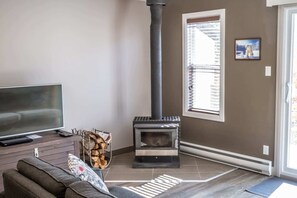 Una sala de estar con televisor, sofá, chimenea y ventana con persianas.