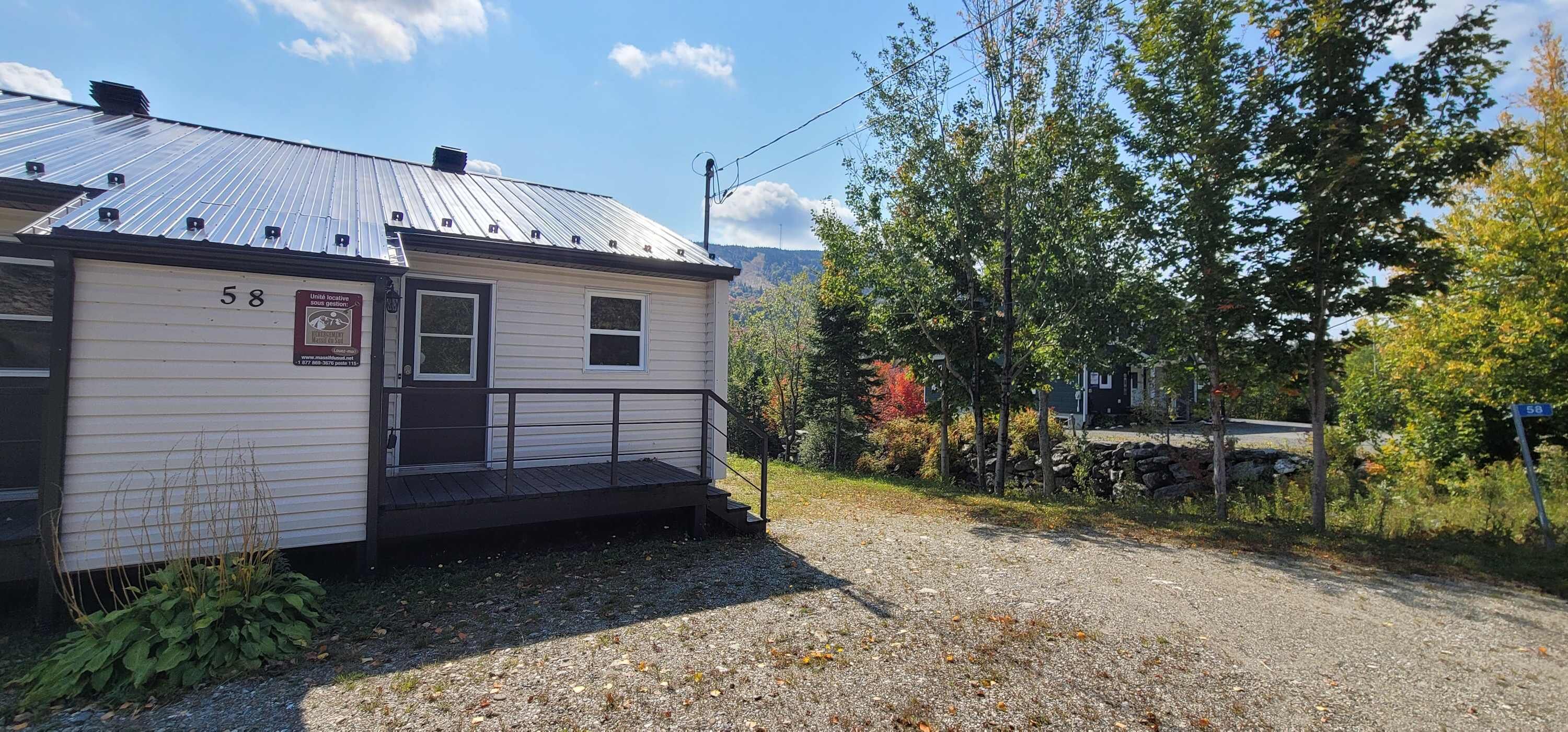 A single-story building with a metal roof, a small porch, and a number '58' sign.