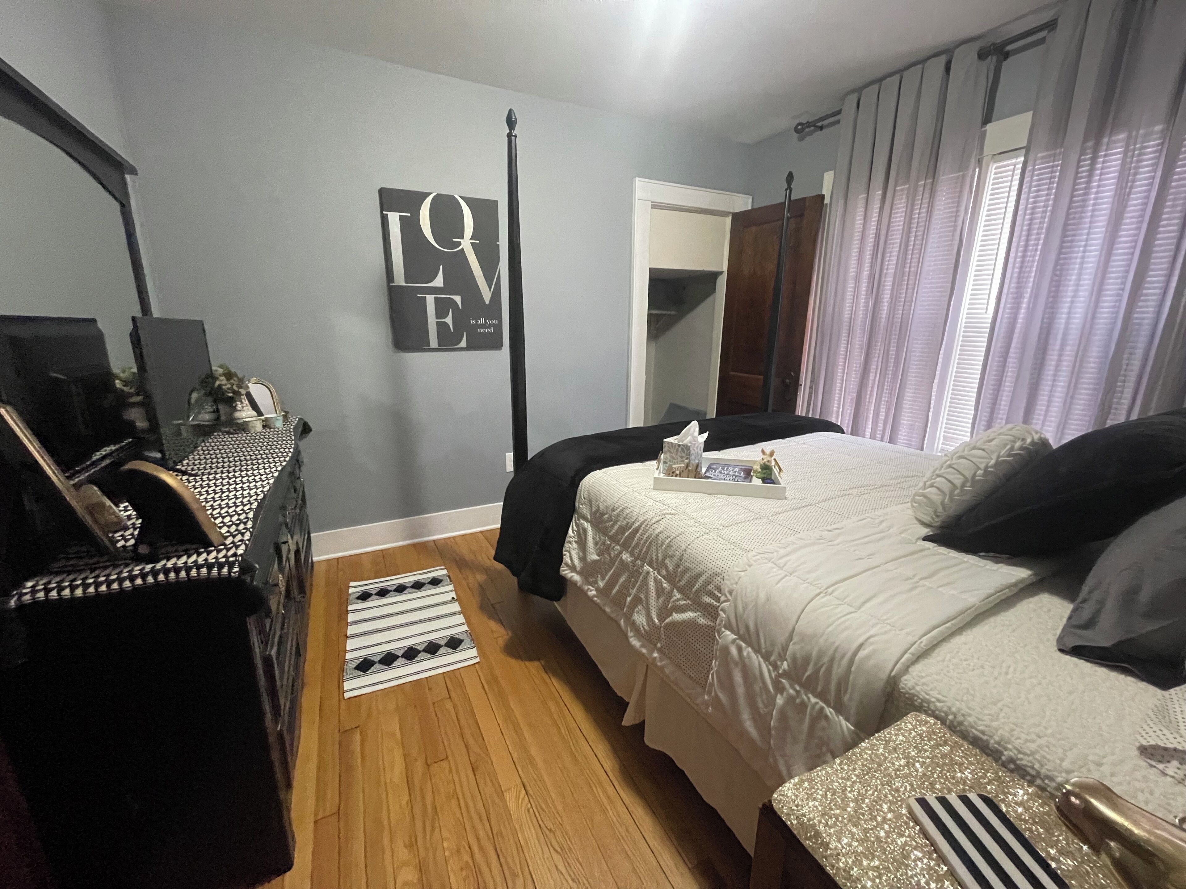 Une chambre à coucher comprenant un lit, une table de chevet, une commode et un miroir.
