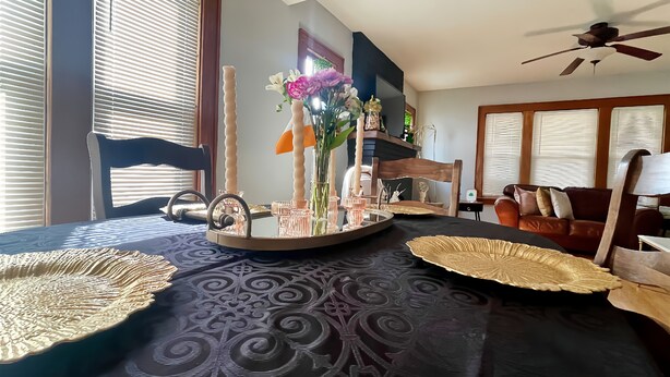 Ein Zimmer mit einem Bett, einem Nachttisch mit Tablett, einem Spiegel und einer Vase mit Blumen.