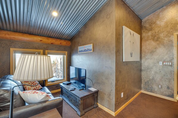 A living room with a leather couch, a TV, and a lamp.