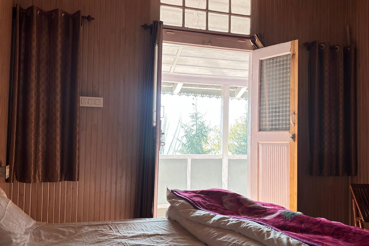 A bedroom with a bed, wooden walls, a window, and a door.