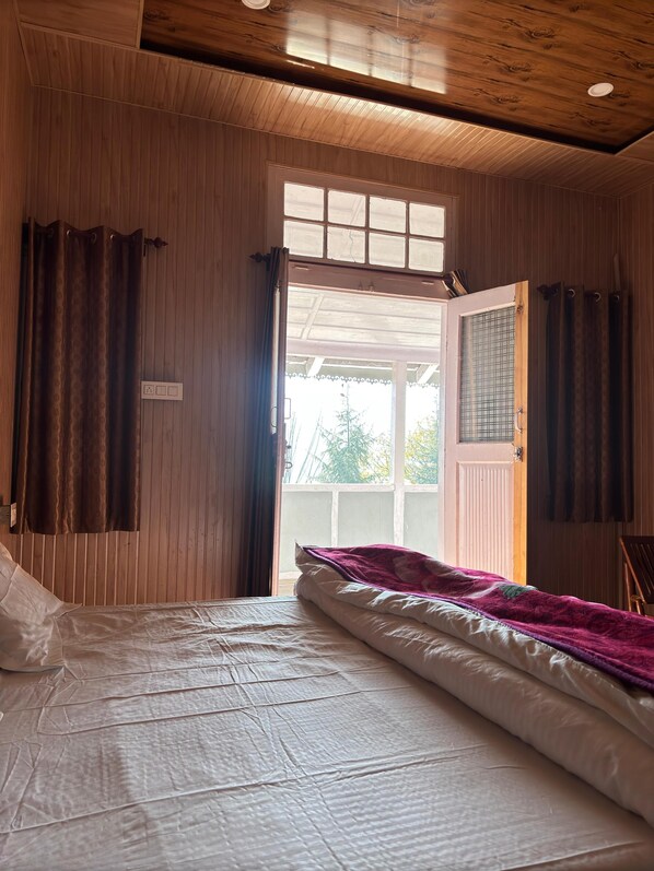 Une chambre à coucher avec un lit, des murs en bois, une fenêtre et une porte.