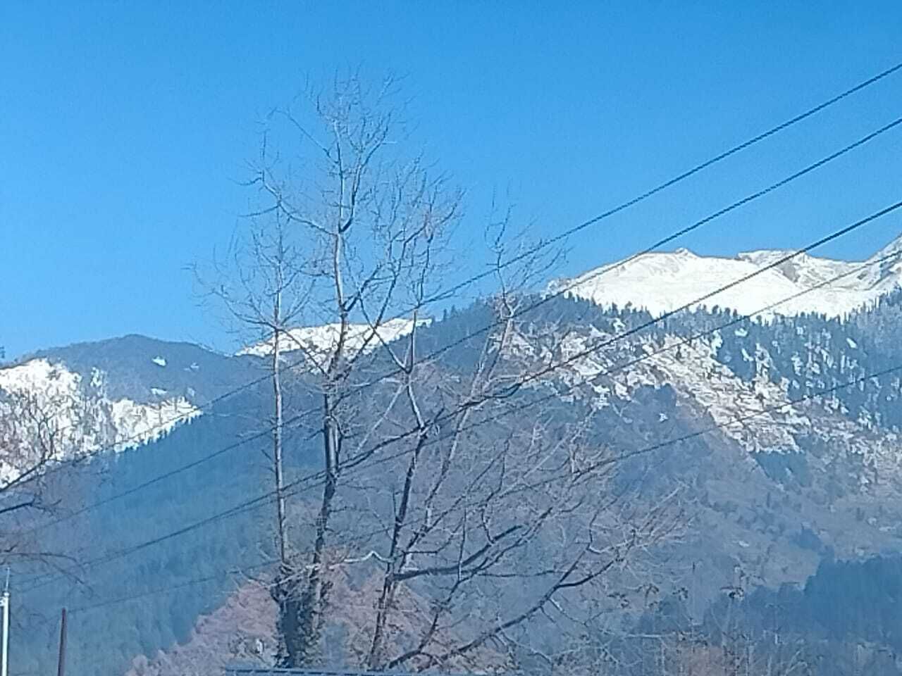 A mountain landscape with snow-capped peaks and a clear blue sky.