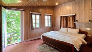 Un dormitorio con techo de madera, una cama grande, una ventana y vistas al verdor exterior.