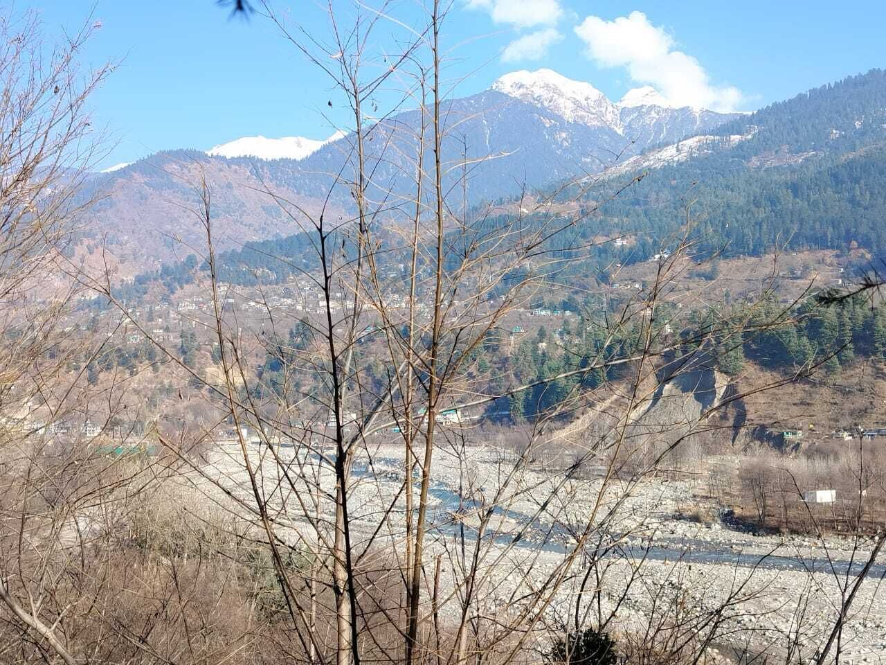 Paisagem montanhosa com picos nevados e um vale abaixo.