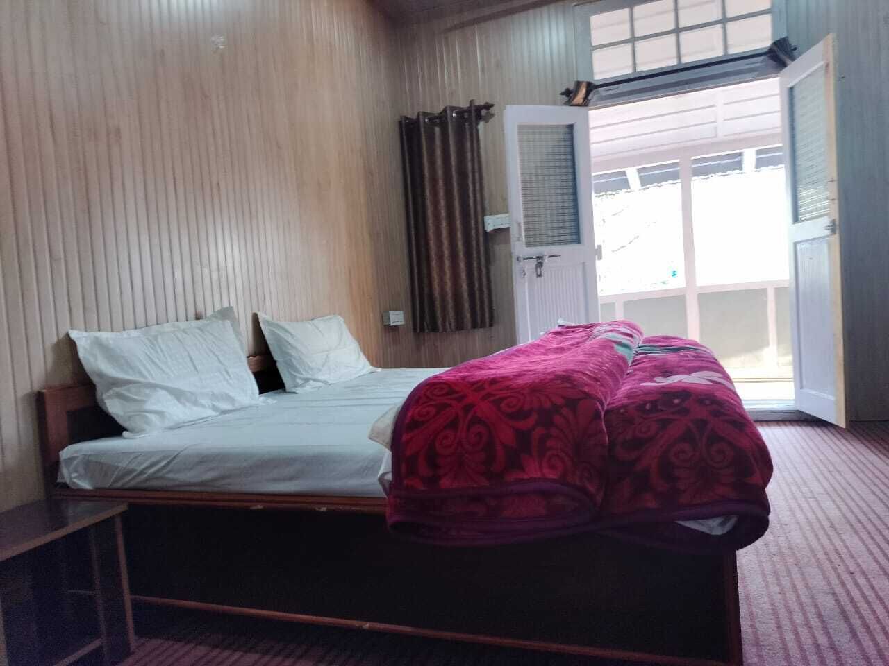 Un dormitorio con cama, ventana con cortinas y puerta.