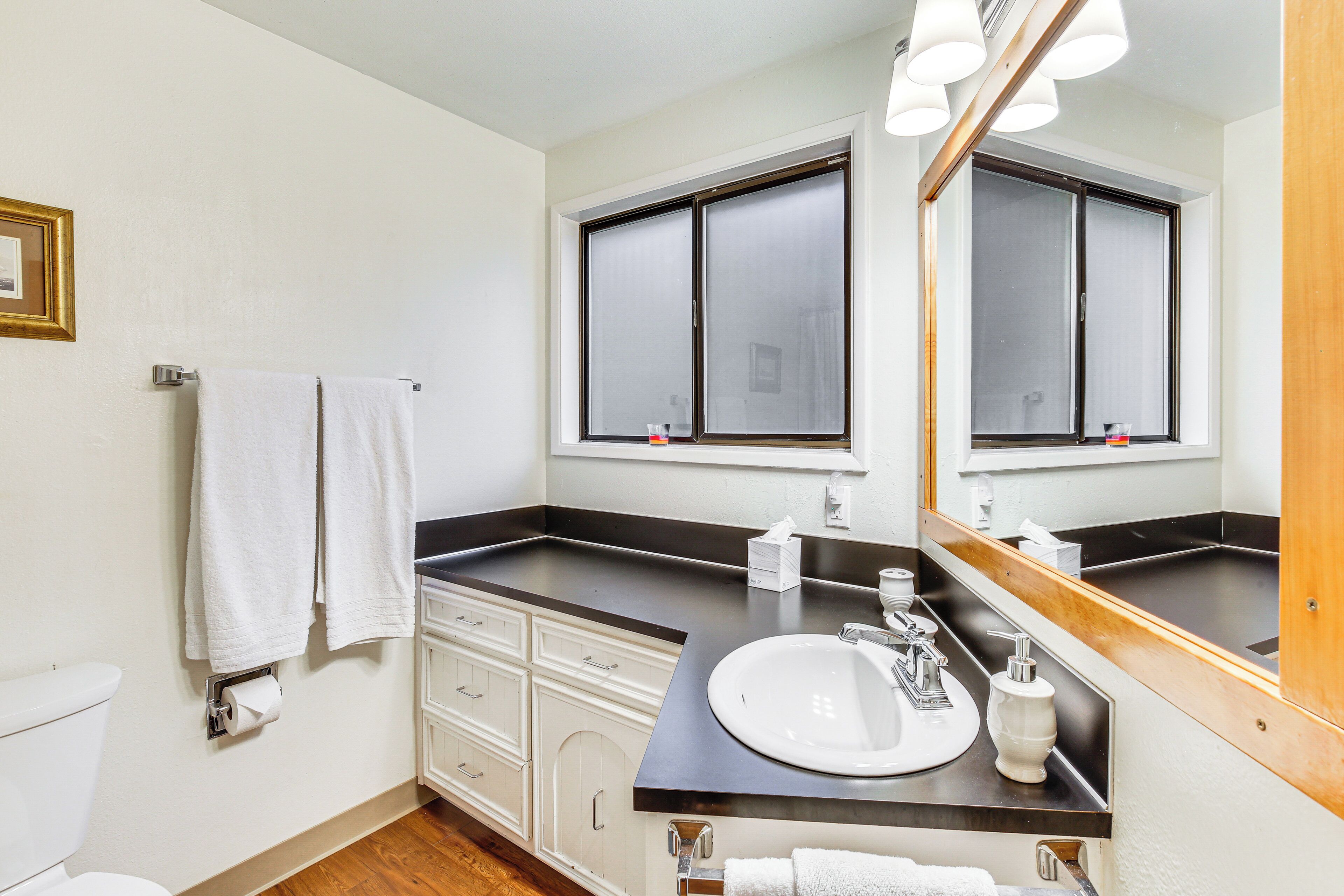 A bathroom with a toilet, two sinks, a mirror, and a window.